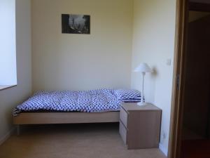 Un dormitorio con una cama y una lámpara en un tocador en La Vannerie en Havelange