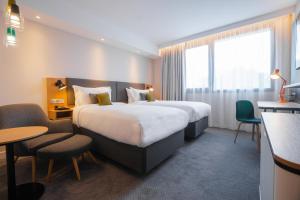 a hotel room with two beds and a table and chairs at Holiday Inn Paris CDG Airport an IHG Hotel in Roissy-en-France +56 photos
