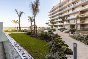 a view of a building with palm trees and a walkway at One River Seixal in Seixal