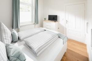 a white bedroom with a bed and a window at Fewo Grete in Norderney