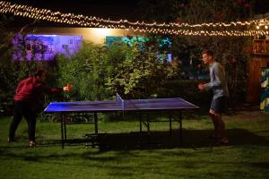 two people standing around a ping pong table at night at White House of Tanzania in Arusha