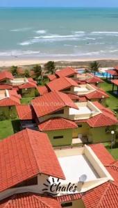 eine Gruppe von Gebäuden mit roten Dächern in der Unterkunft Chalé condomínio beira mar em Zumbi Beach Resort in Rio do Fogo