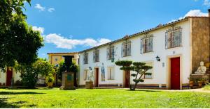 um grande edifício branco com um relvado em La Estancia Villa Rosillo em Aracena