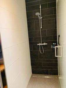 ein Bad mit einer Dusche und einer schwarzen Kachelwand in der Unterkunft Bed & Breakfast "aan de banis" in Rijssen