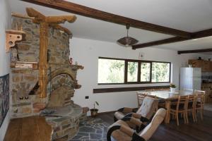 uma sala de estar com uma lareira de pedra e uma mesa em Къща за гости "Касапите" em Kameshtitsa