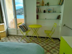 ポール・ヴァンドルにあるAppartement La Méditerranée vue sur Mer plein soleil 3 climatisations réversiblesのテーブルと椅子2脚、窓が備わる客室です。
