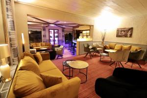 a living room with a couch and tables and chairs at Hotel Val de l'Our in Burg-Reuland