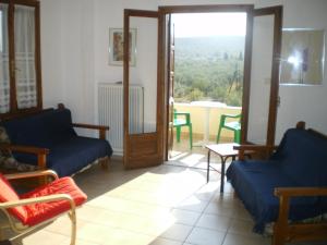 - un salon avec deux chaises bleues et une fenêtre dans l'établissement Villa Christina, à Amaliápoli
