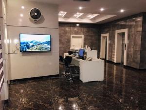 an office with a desk and a tv on a wall at Royaute Luxury Hotel Sialkot in Sialkot