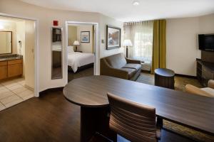 ein Hotelzimmer mit einem Tisch und einem Wohnzimmer in der Unterkunft Candlewood Suites Windsor Locks, an IHG Hotel in Windsor Locks