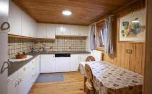 eine Küche mit weißen Schränken und einem Tisch im Zimmer in der Unterkunft Lüch de Martin in Wengen