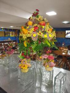 stół z wazami wypełnionymi kwiatami i owocami w obiekcie Flat 406- Imperial Flat Tambaú NOBILE w mieście João Pessoa