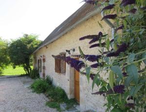 un bâtiment avec des fleurs violettes sur son côté dans l'établissement Chambres d'Hôtes L’Échappée Belle, à Saint-Brisson-sur-Loire