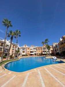 een groot zwembad met palmbomen en gebouwen bij Apartament Claudia II in Puerto de Mazarrón