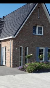 una casa de ladrillo con ventanas y flores en una entrada en De Sprink - Vakantiewoning, en Zoutelande