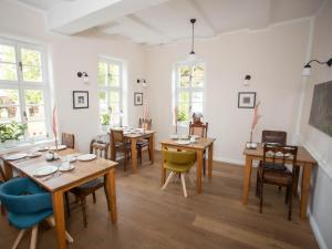 a dining room with tables and chairs and windows at Altstadthotel Treysa in Schwalmstadt