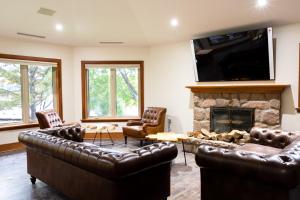 a living room with leather furniture and a fireplace at Fairy Bay Lakehouse in Huntsville
