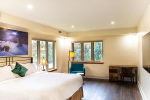 a bedroom with a bed and a desk and windows at Fairy Bay Lakehouse in Huntsville