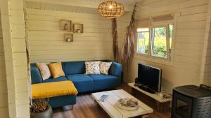 a living room with a blue couch and a tv at Casa Ibiza is vakantie in Drenthe in Schoonebeek