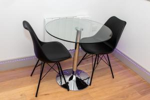 two black chairs and a glass table in a room at Stunning 1-Bedroom flat in London! in London