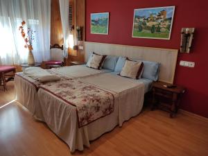 a bedroom with a large bed with red walls at Hostal Escartín in Sabiñánigo