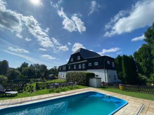 a house with a swimming pool in front of a building at Penzion Hubertus Doubice in Doubice