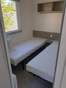 two beds in a small room with a window at Louons ensemble in Saint-Jean-de-Monts