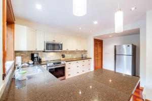 a kitchen with white cabinets and a stainless steel refrigerator at Greyhawk by Outpost Whistler in Whistler