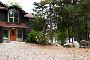 a house with a red door and a gravel driveway at Fairy Bay Lakehouse in Huntsville