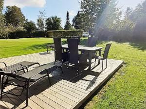 een picknicktafel en stoelen op een houten terras bij 5 person holiday home in Odder in Odder