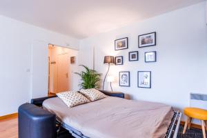 a bedroom with a bed with a chair and pictures on the wall at ANJA - Top Hôte Paris - 6 Personnes Balcon Parking in Saint-Denis