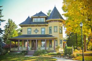 Una gran casa amarilla con un reloj. en Ruby Manor Bed & Breakfast, en Gananoque