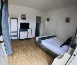 ein kleines Schlafzimmer mit einem Bett und einem TV in der Unterkunft Paradise Beach Guest House in Bantayan