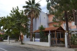 a white building with a porch and palm trees at Filoxenia Hotel in Volos