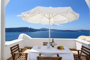 a table with a white umbrella and a plate of fruit at Top Oia in Oia