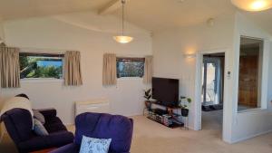 - un salon avec deux chaises et une télévision dans l'établissement Kimberley Three - Nelson Waterfront Penthouse, à Nelson