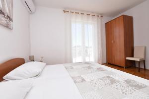 a white bed in a room with a window at Rooms Bozena in Primošten