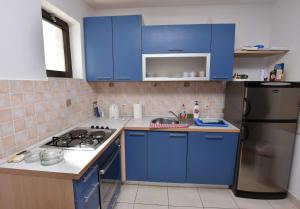 a kitchen with blue cabinets and a stainless steel refrigerator at Rooms Bozena in Primošten +32 photos