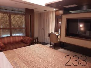 a hotel room with a bed and a flat screen tv at Chateau Motel & Spa (Daliao) in Daliao