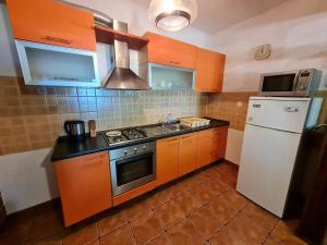a kitchen with orange cabinets and a white refrigerator at Apartment Andrea in Klenovica +13 photos