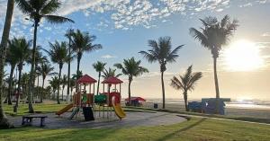 a playground on the beach with palm trees at Villagio Aloha Beach in Bertioga