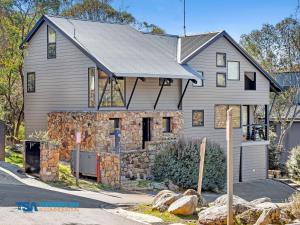 a large house with a stone wall at Ramshead Creek 1 in Thredbo