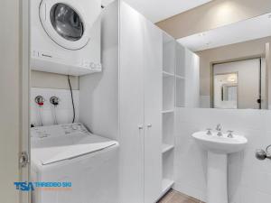 a white bathroom with a sink and a mirror at Ramshead Creek 1 in Thredbo
