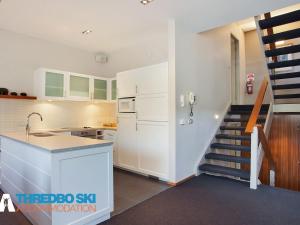 a kitchen with white cabinets and a staircase at Ramshead Creek 2 in Thredbo