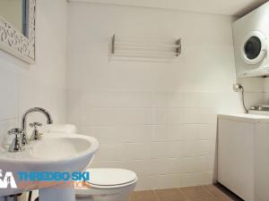 a white bathroom with a toilet and a sink at Ramshead Creek 2 in Thredbo