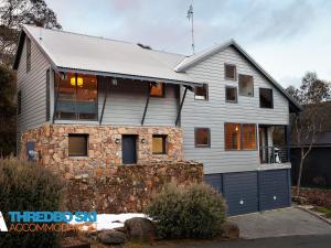 a white house with a stone wall at Ramshead Creek 2 in Thredbo