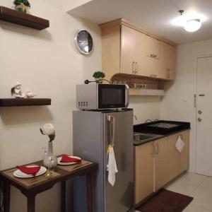 uma pequena cozinha com um frigorífico e uma mesa em EMSMAR 908 Wind Residences Tagaytay em Tagaytay