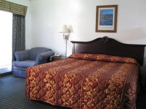 ein Hotelzimmer mit einem Bett und einem Stuhl in der Unterkunft Jamestown Railtown Motel in Jamestown