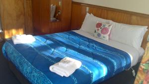a bedroom with a large bed with towels on it at Otaki Motel in Otaki