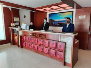 Tres hombres con máscaras parados en un mostrador de recepción en Comfort Inn Benares en Varanasi